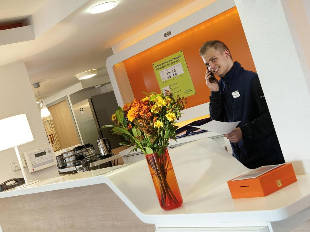a man talking on a cell phone at a counter at ibis budget Orgeval in Orgeval