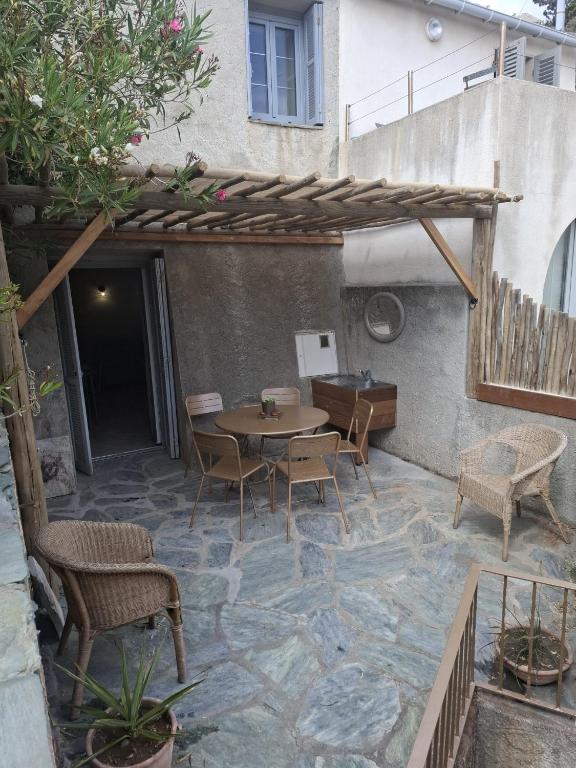 an outdoor patio with a wooden table and chairs at Maison Milani Centuri in Centuri