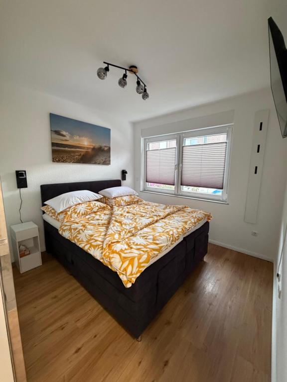 a bedroom with a large bed and two windows at Ferienwohnung Janni in Bad Zwischenahn