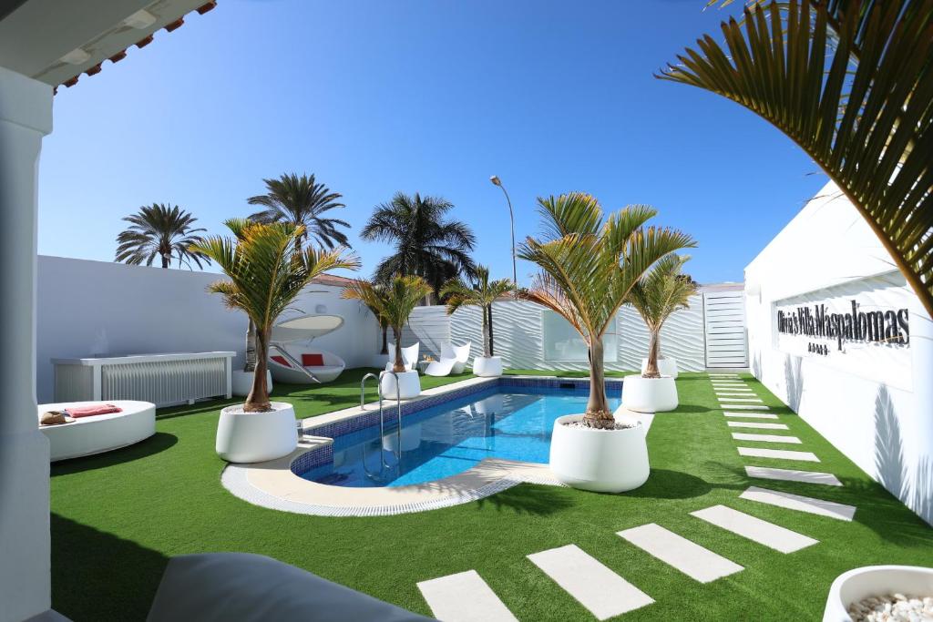 a courtyard with palm trees and a swimming pool at Olivia Holidayhouse Maspalomas in Maspalomas