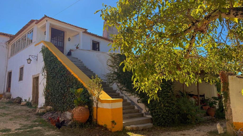 a white house with a staircase in front of it at Quinta Da Carvalheira Regenerative Coliving in Soure