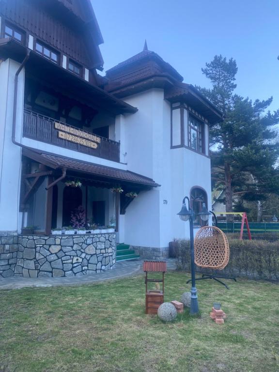 a white house with a playground in the yard at White Wood Chalet in Buşteni