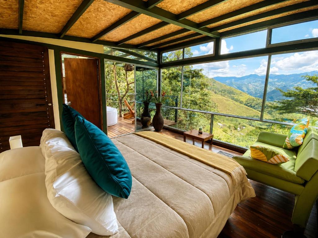 a bedroom with a large bed and a large window at ANCESTRAL GLAMPING in Barbosa