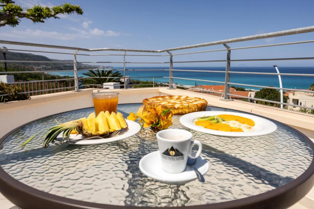 a table with two plates of food and a drink at San Carlo - Terrazzo sul Mare con Ristorante e Pizzeria in Zambrone