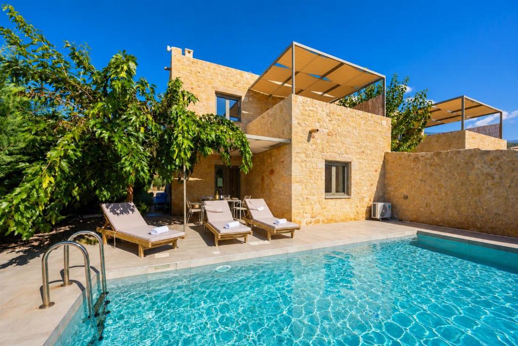 a swimming pool with chairs and a house at Villa Castillo Ena in Agios Nikolaos