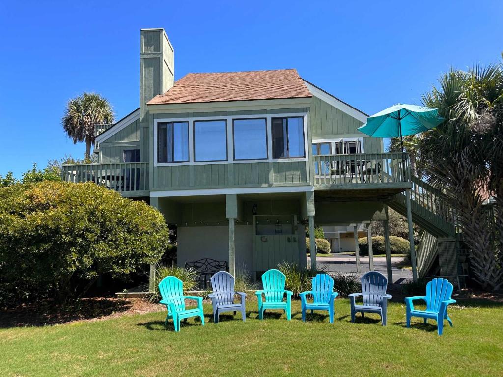 a group of chairs and an umbrella in front of a house at 915 Sealoft Villa in Seabrook Island