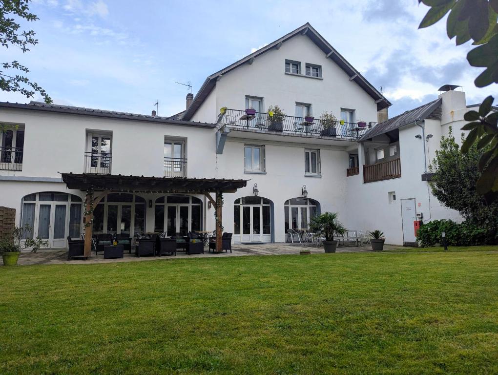 a large white house with a green lawn at Hôtel de l'Ours in Arette