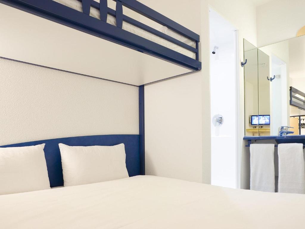 a bedroom with a bed and a mirror at ibis budget Bar le Duc in Bar-le-Duc