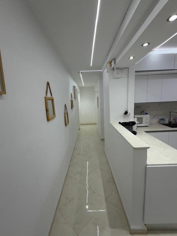 a kitchen with white walls and a long hallway at Escapade urbaine moderne in Sétif