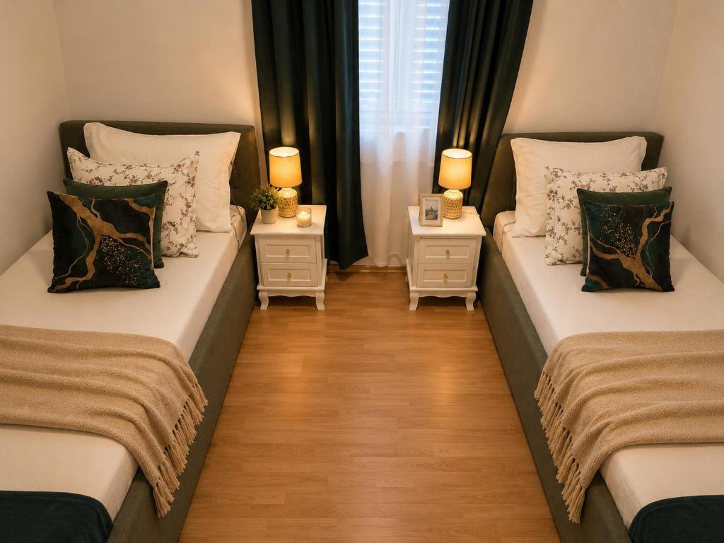 two beds in a room with two side tables at Apartman David in Postira