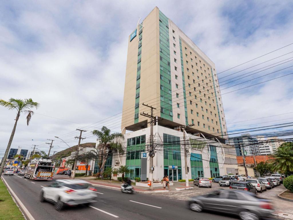 a tall building on a busy city street with cars at ibis budget Vitoria in Vitória
