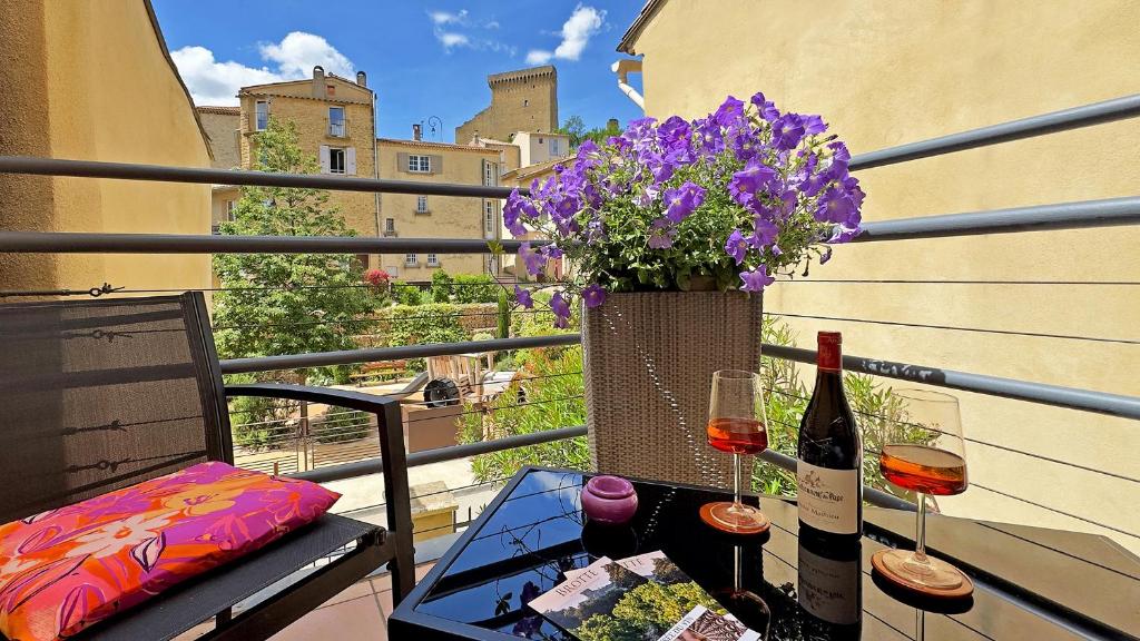 a balcony with two glasses of wine and a vase of flowers at L'AMARILYS chambre d'hôte au coeur du village, terrasse avec vue sur le château in Châteauneuf-du-Pape
