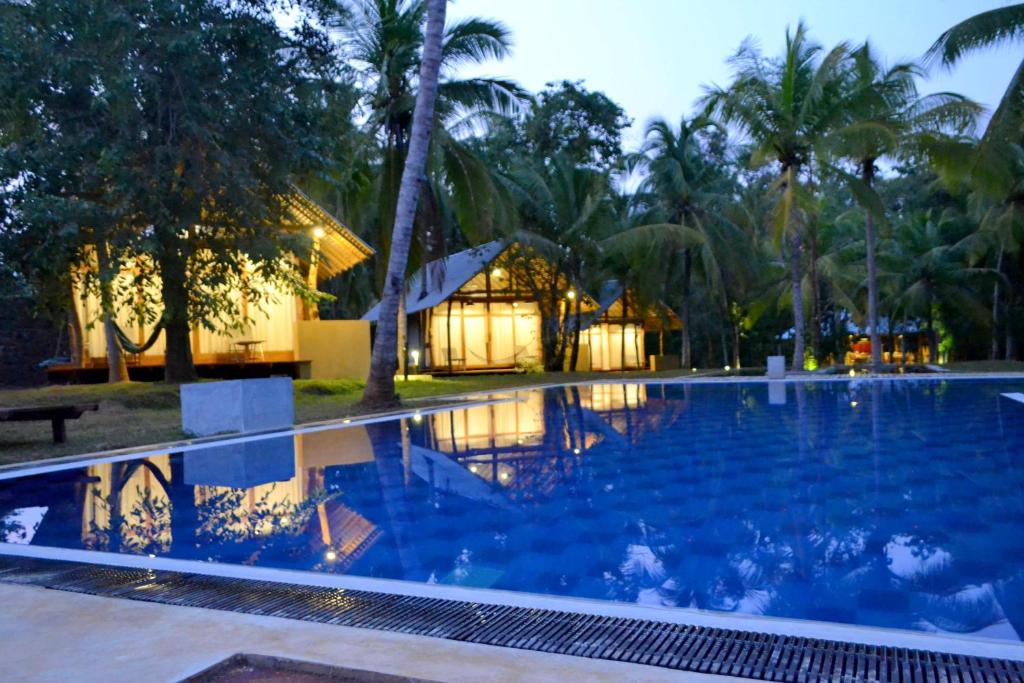 a large swimming pool in front of a resort at Kottawatta Village in Udawalawe