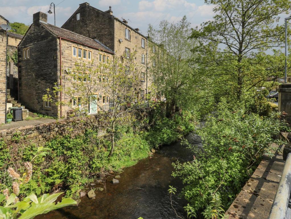 a river in front of an old building at Riverview Cottage in Holmfirth