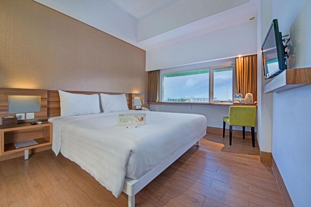 a hotel room with a large bed and a desk at Whiz Prime Hotel Balikpapan in Balikpapan
