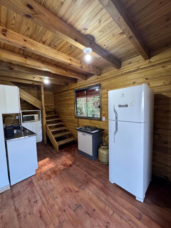 a kitchen with white appliances in a log cabin at Cabanas da zimba in Imbituba