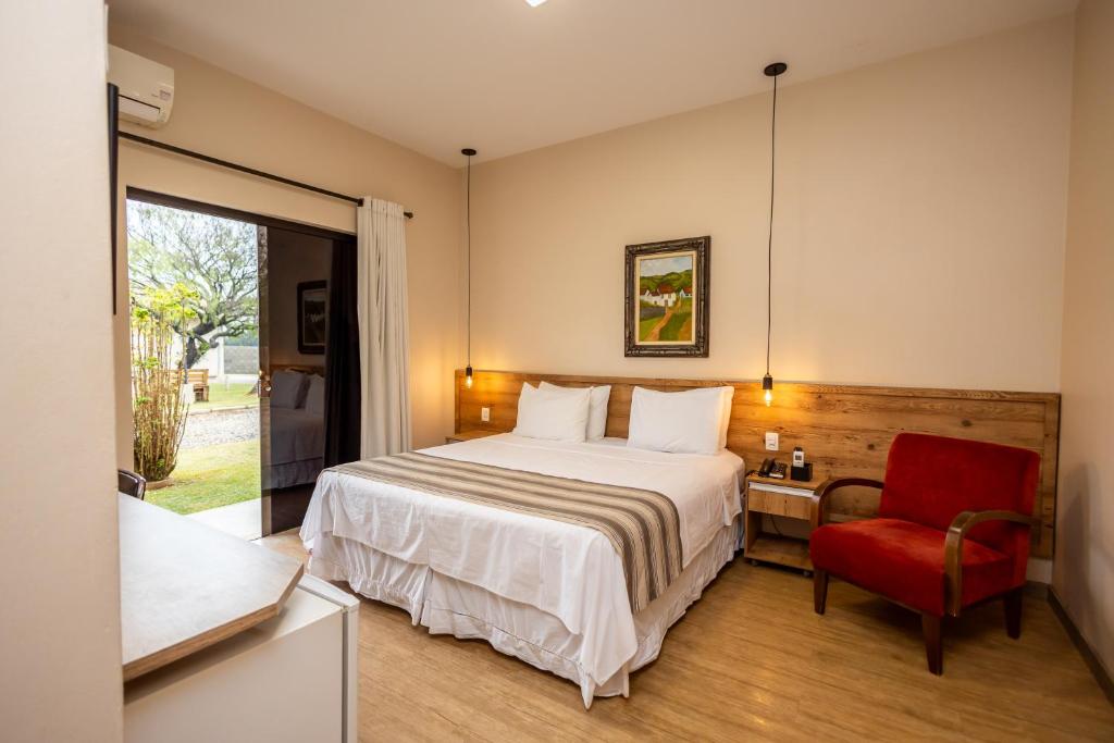 a bedroom with a bed and a red chair at Rancho das Pedras Itaberá in Itaberá