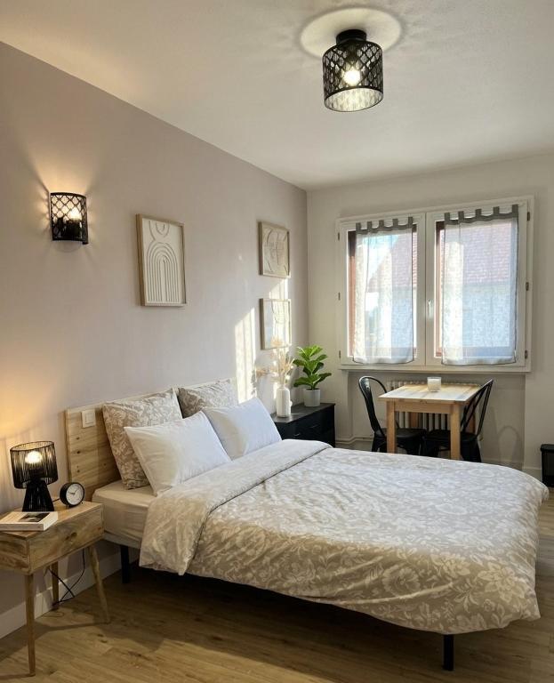 a bedroom with a large bed with a table and a dining room at Le Minimaliste Chic in Montbrison