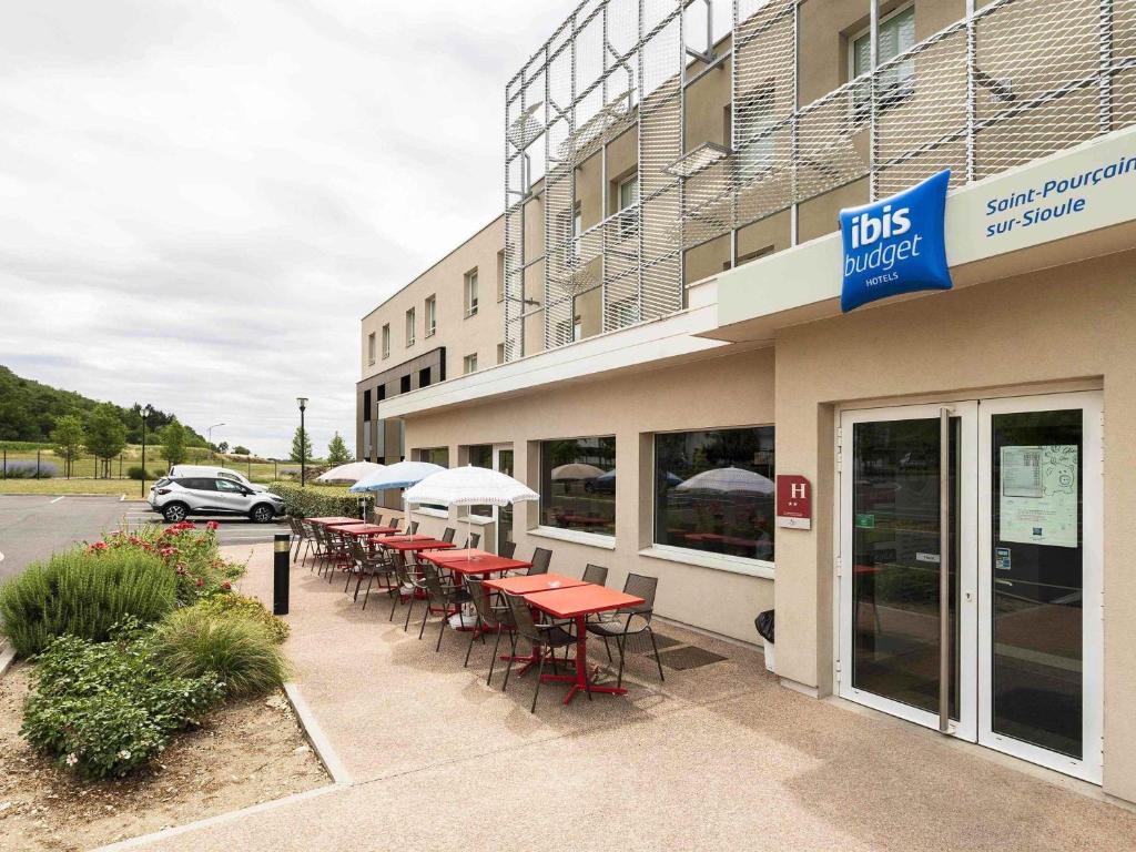 a restaurant with tables and chairs outside of a building at ibis budget Saint Pourcain in Saint-Pourçain-sur-Sioule