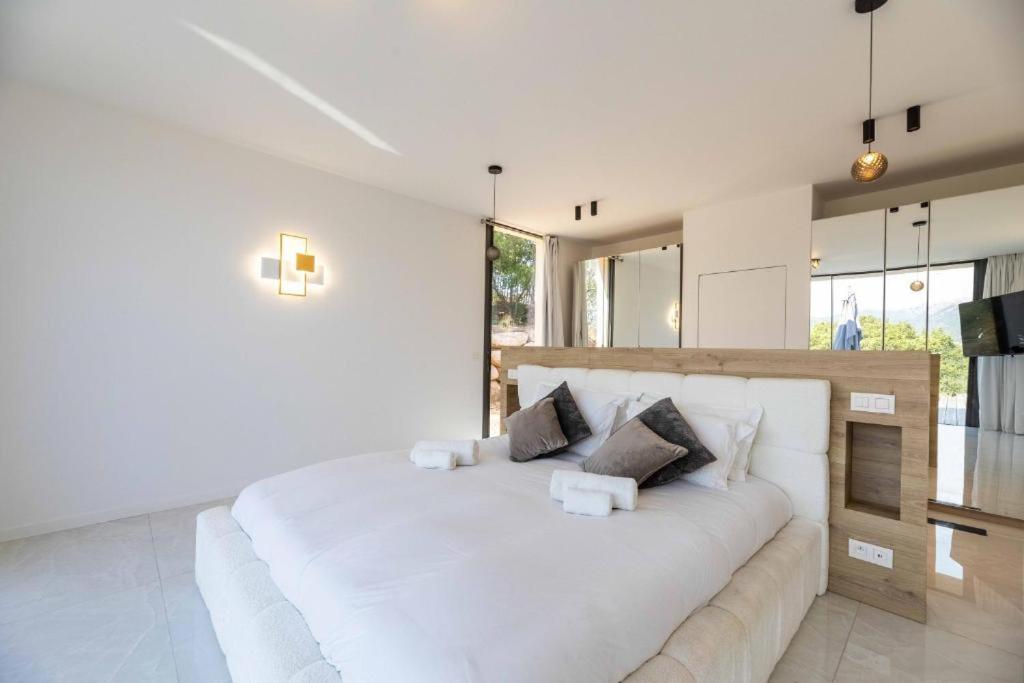 a white bedroom with a large white bed with two pillows at Hotel Monte Sereno in Zonza