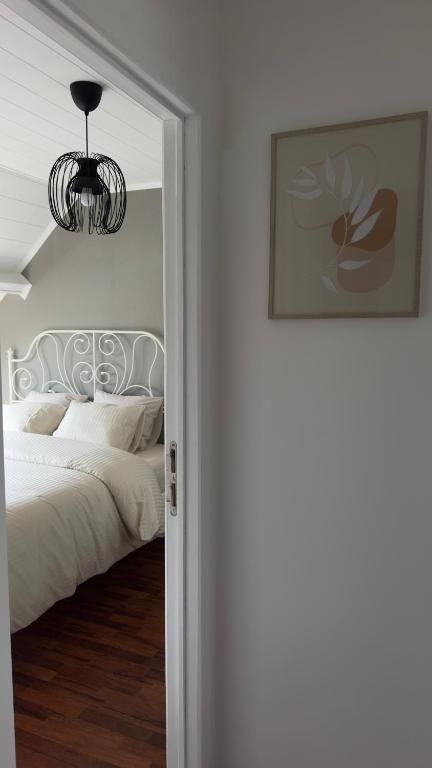 a bedroom with a white bed and a chandelier at Countryside house by Pairi Daiza in Silly