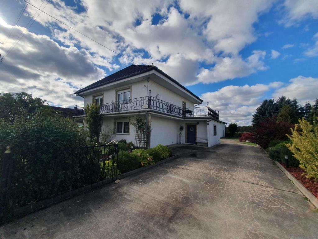 a white house with a balcony on a driveway at White House in Gronów