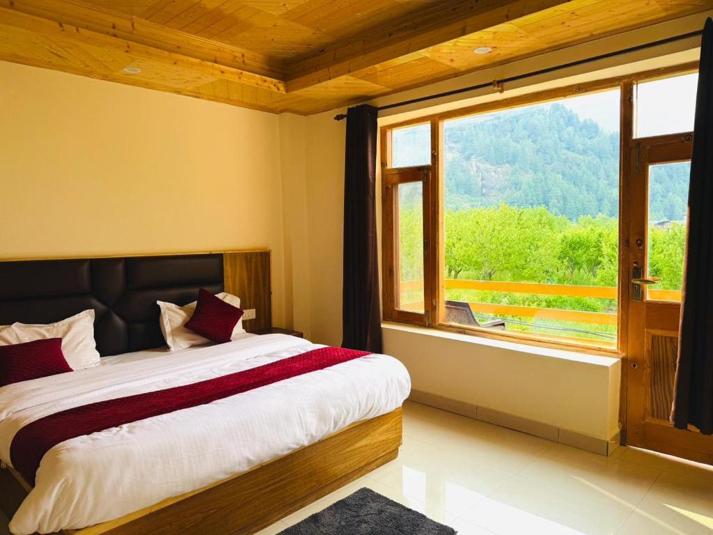 a bedroom with a bed and a large window at Hotel Deluxe Inn Manali in Manāli