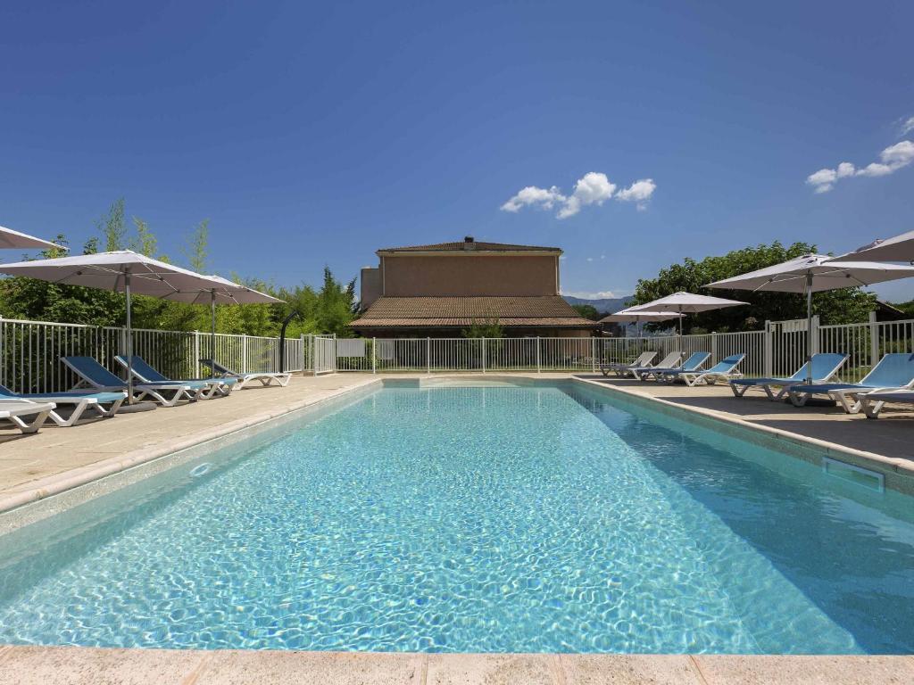 a large swimming pool with chairs and umbrellas at Ibis Budget Sisteron in Sisteron
