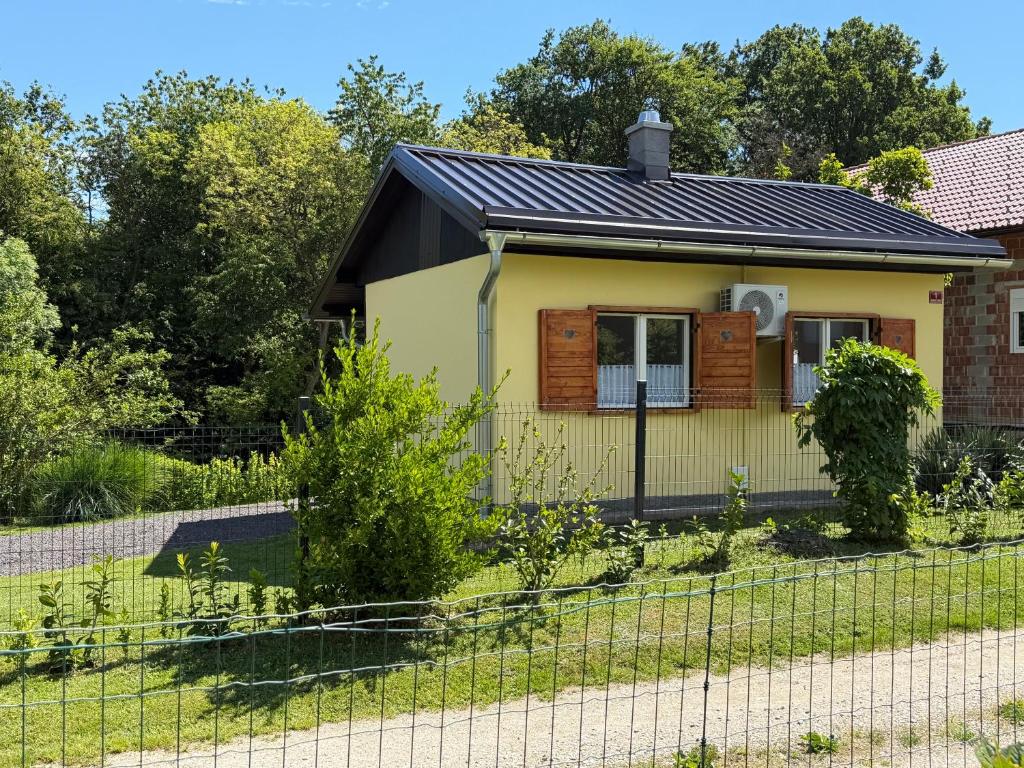 a small yellow house with a black roof at Počitniška hiša ˇGORICEˇ in Moravske-Toplice