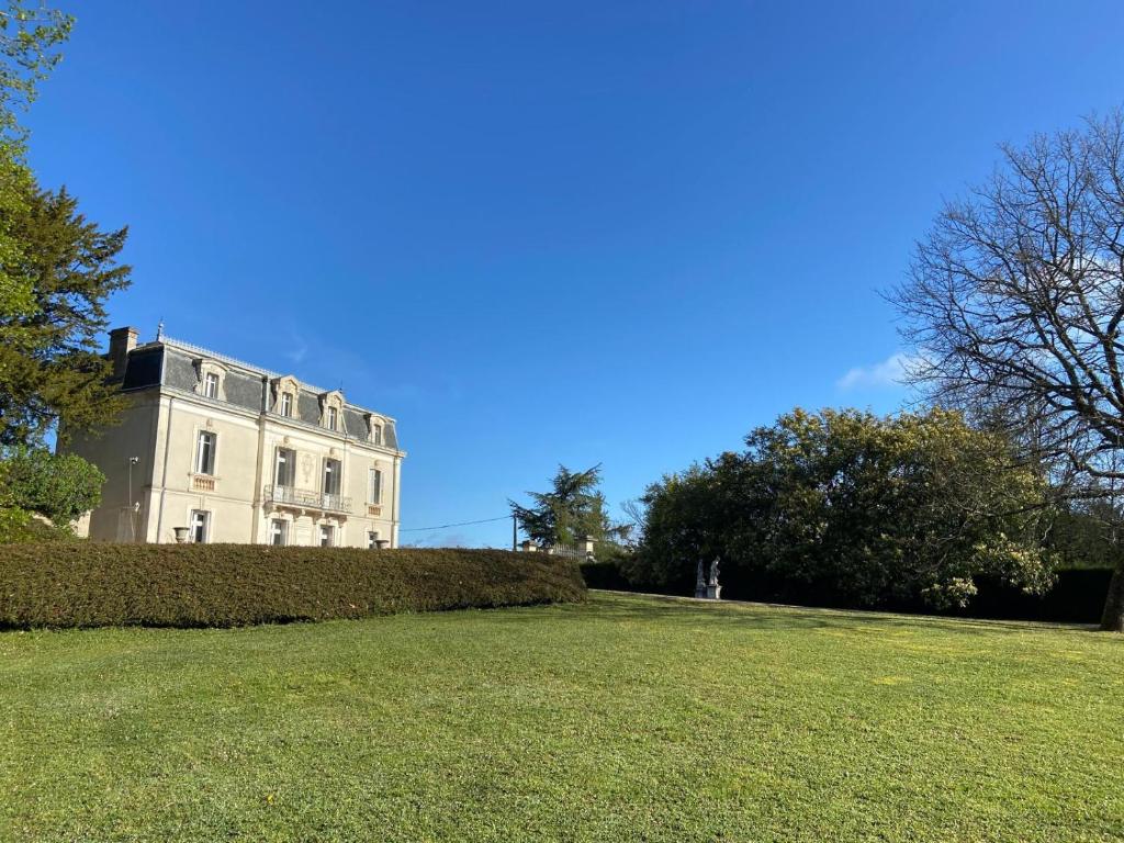 a building with a hedge in front of a field at Chateau de Briand in Luxé