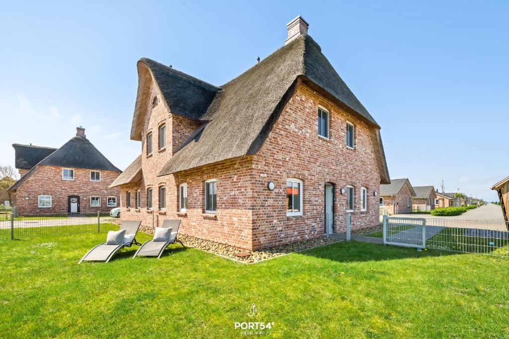 an old brick house with two chairs in the yard at Ferienhaus Philomena Dagebüll in Dagebüll
