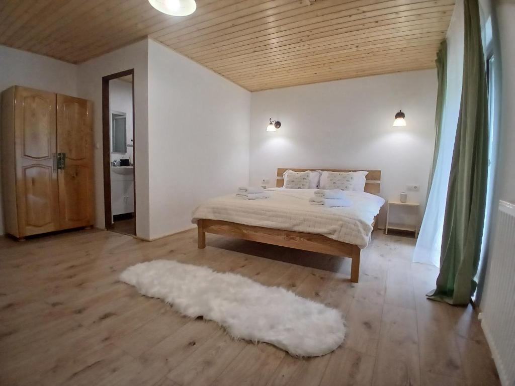 a bedroom with a bed and a rug at Hanul Ibăștean in Brădeţelu