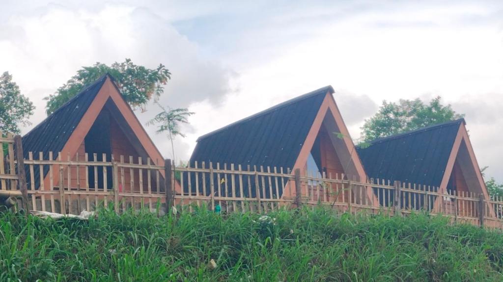 a large wooden house with a wooden fence at Cihulu Budget Glamping in Tengahgirang