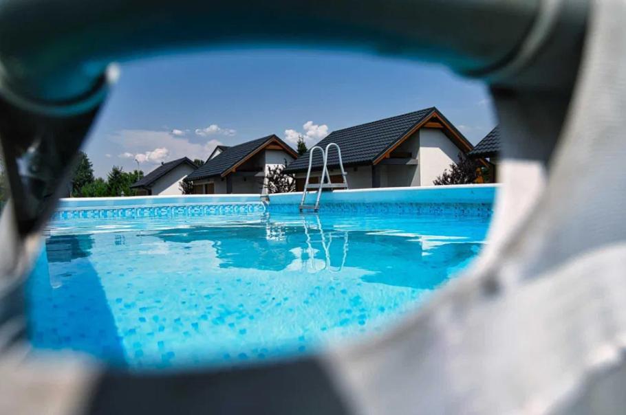 a reflection of a swimming pool with a house at Apartamenty i Domki u Basi in Zator