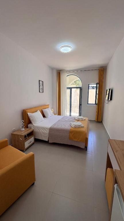 a large bedroom with a bed and a couch at Drymades Ruci Rooms in Dhërmi