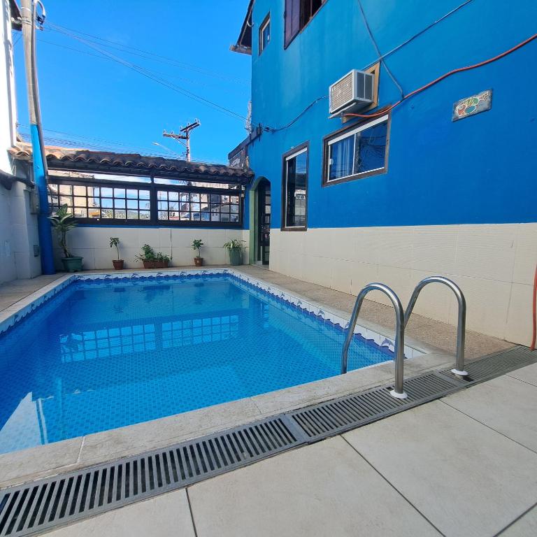 a swimming pool in front of a blue building at Pousada Mandala - Búzios in Búzios