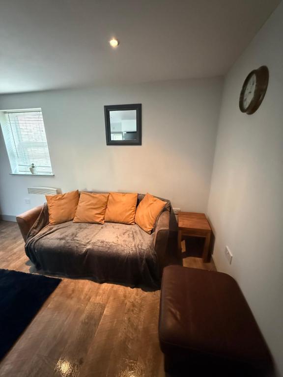 a couch in a living room with a clock on the wall at Stonebarn New in Halton