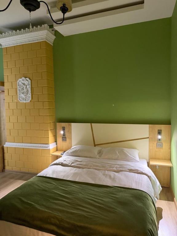 a bedroom with a green wall and a large bed at Three Colour Rooms in Kutaisi