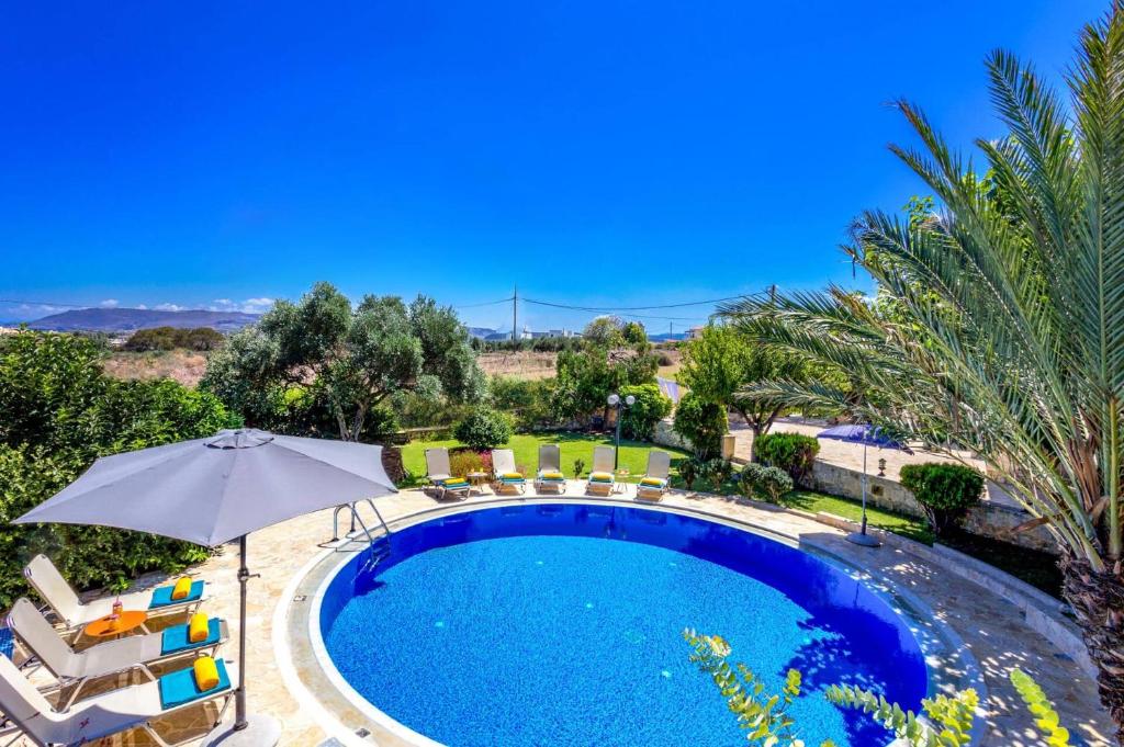 a swimming pool with chairs and an umbrella at Villa Avra by Villa Plus in Asprouliánoi