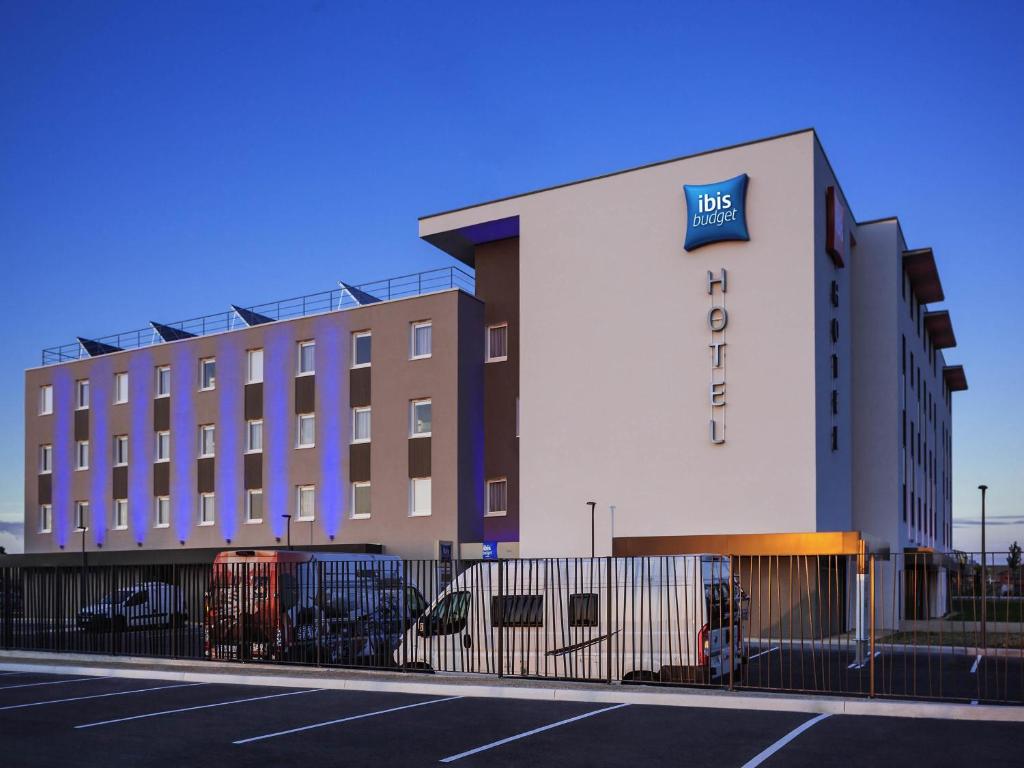 a hotel with a fence in front of a building at ibis budget Sens in Sens