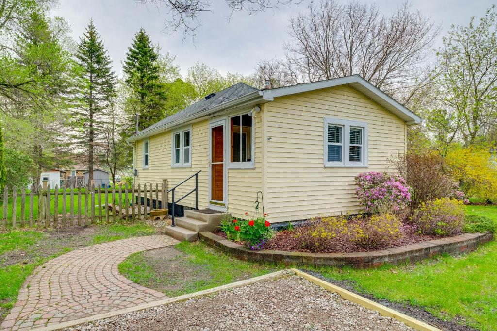 a small yellow house with a porch and flowers at Blocks to Beach & Eats! Elk Rapids 'Cozy Cottage' in Elk Rapids