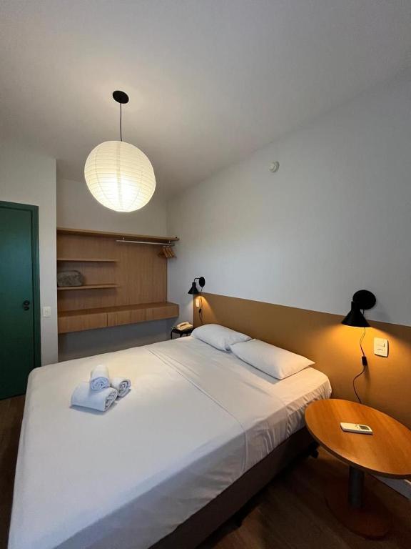 a bedroom with a large white bed and a table at Summit Flat São José dos Campos in São José dos Campos