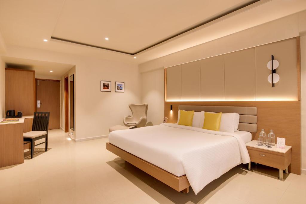 a bedroom with a large white bed and a desk at Regenta Place CG Road in Ahmedabad
