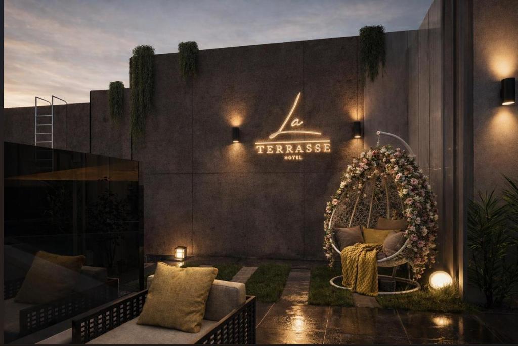 a patio with a swing and a sign on a wall at La Terrasse Hotel in Jeddah