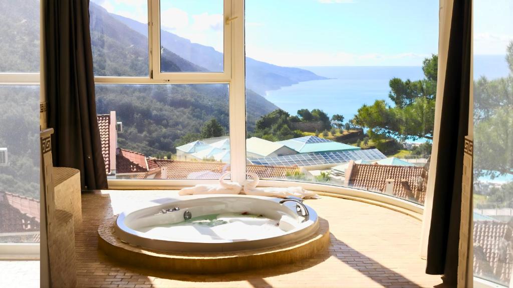 a bath tub in a room with a large window at Azure Palm Resort in Oludeniz