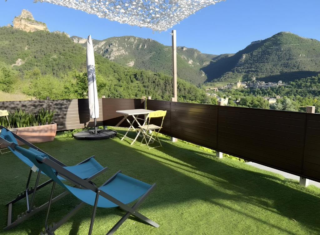 a patio with a chair and a table and mountains at Appartement Gorges du Tarn in Mostuéjouls