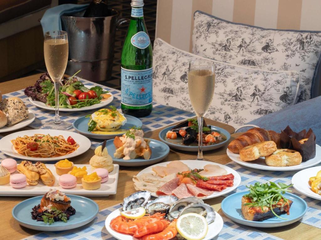 A generously styled spread includes pastries, seafood, salads, pasta and sparkling drinks.