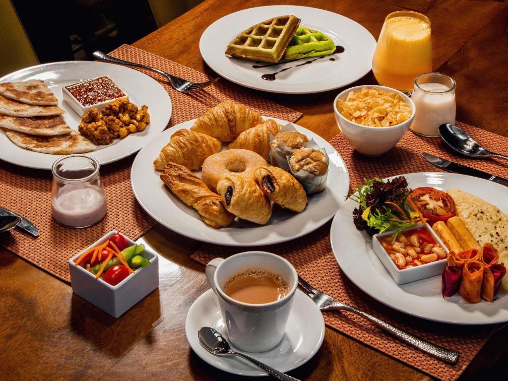A broad breakfast spread featuring pastries, waffles, fruit, cereal, and hot dishes.