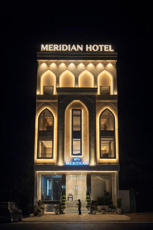 a night view of a hotel with a sign on it at Hotel Meridian in Jagādhri