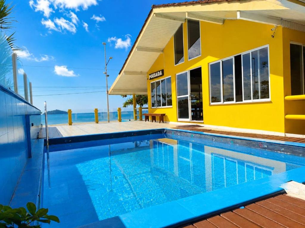 a yellow house with a swimming pool in front of it at Mansão Ouro Verde Beira Mar in Piçarras